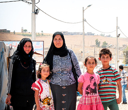 Photo of a refugee family standing together on a street.